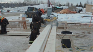 Construction worker operates a DeWalt circular saw on a work site; construction equipment visible in the background